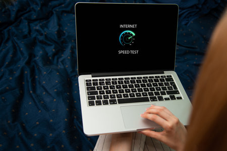 Woman using a laptop on a bed with a speedometer app on the screenの写真素材
