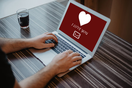Man using laptop at table against valentines message on laptop screenの写真素材