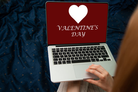 Woman using a laptop with valentines day concept on the screenの写真素材