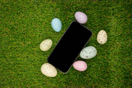 Phone with blank empty screen on 
green grass background of easter eggsの写真素材