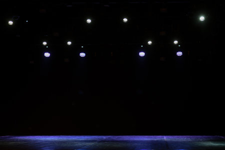 Empty stage lighting setup with red, yellow, and blue spotlights shining down, creating a dramatic atmosphere on a dark backdrop, perfect for concert or theater scenes.の写真素材