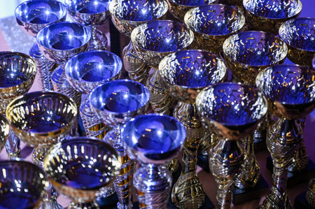 Elegant silver trophies with deep blue glass bowls arranged in rows, captured in dramatic lighting. Ideal visual for awards ceremonies, achievement, competition success, business recognition and premium events.の写真素材
