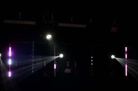 Powerful stage spotlights casting bright beams across a dark indoor venue. Professional concert and...