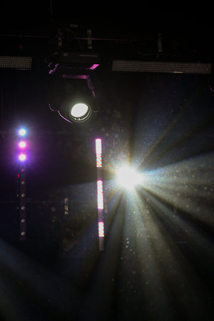 Intense stage spotlight projecting strong light rays through haze in a dark venue. Professional...