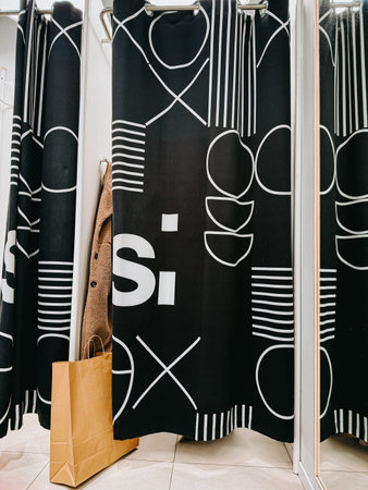 Riga, Latvia - April 4, 2026:Modern retail fitting room with bold black patterned curtain, mirror...
