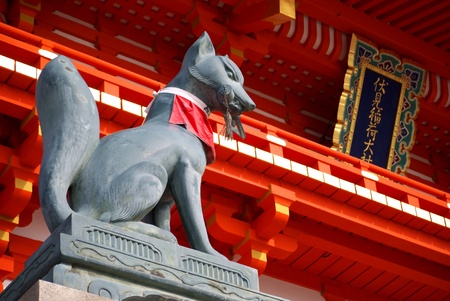 A stone fox statue stands guard over the entrance of Fushimi Inari.のeditorial素材