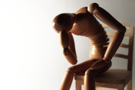 worried wooden dummy sitting with copy spaceの写真素材