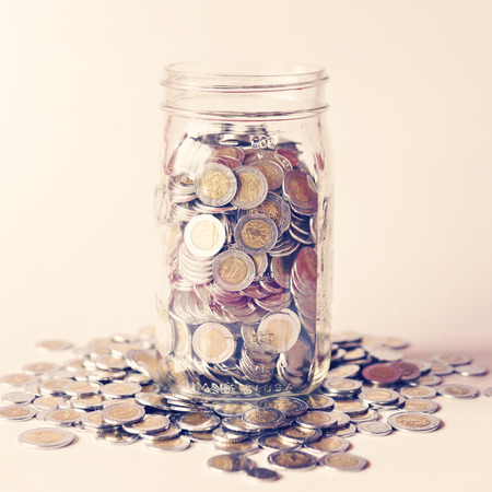 glass jar with full of mexican pesos coins with vintage color tone processの写真素材