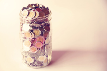 glass jar with full of mexican pesos coins with vintage color tone processの写真素材