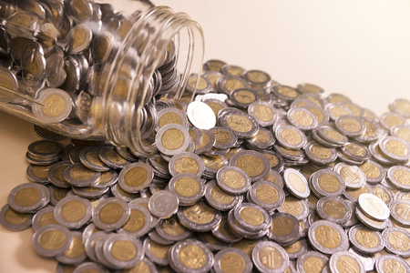 glass jar with many mexican pesos coinsの写真素材