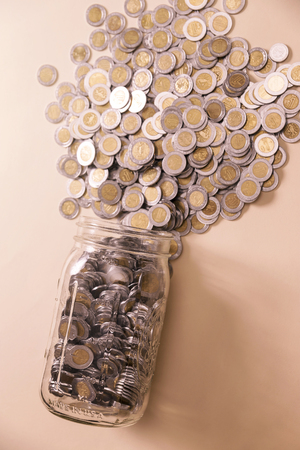 glass jar with many mexican pesos coinsの写真素材