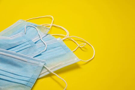disposable blue medical face masks to prevent infection on yellow background. useful for pandemic COVID19 conceptの写真素材