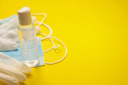 medical latex gloves, protective masks and hand sanitizer gel bottle for protection on yellow background. Useful for pandemic prevention conceptの写真素材