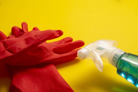 red rubber gloves and liquid detergent in sparay bottle on yellow background, cleaning and sanitization conceptの写真素材