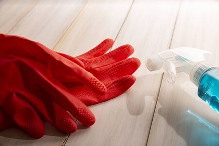 red rubber gloves and liquid detergent in sparay bottle on wooden background, cleaning and sanitization conceptの写真素材