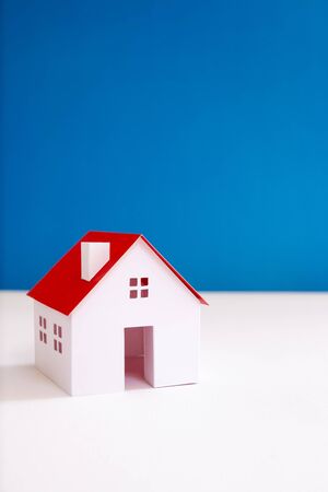 white paper miniature house with red roof on blue color backgroundの写真素材