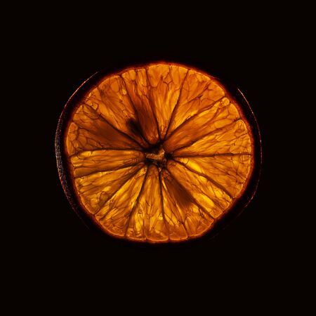 slice og mature orange fruit with backlight isolated on black backgroundの写真素材