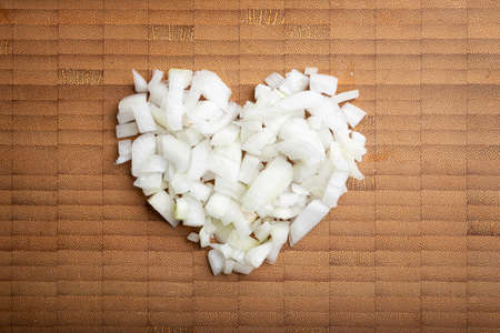 love concept image of heart shape made of diced onion on bamboo cutting board backgroundの写真素材