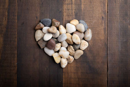 love concept image of heart shape made of round pebbles on wooden backgroundの写真素材