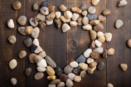 love concept image of heart shape frame made of round pebbles on wooden backgroundの写真素材