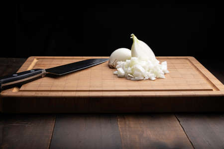 Fresh diced white onion on bamboo cutting board. Allium cepa. Black backgroundの写真素材