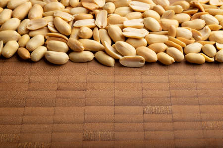 peeled peanuts seeds close up on bamboo wooden background for copy space. (arachis hypogaea) Edible seeds. Healthy snack nutrition conceptの写真素材