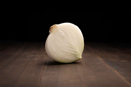image of a half an onion close up on rustic wooden surface and black backgroundの写真素材