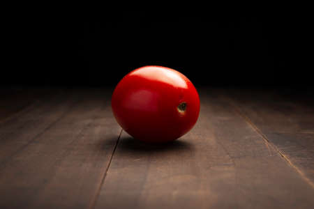 image of a tomato close up on rustic wooden surface and black backgroundの写真素材