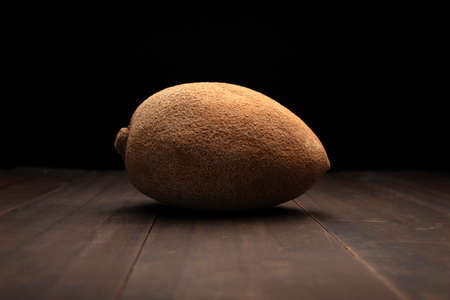 still life image of one mexican red mamey close up on rustic wooden surface and black backgroundの写真素材