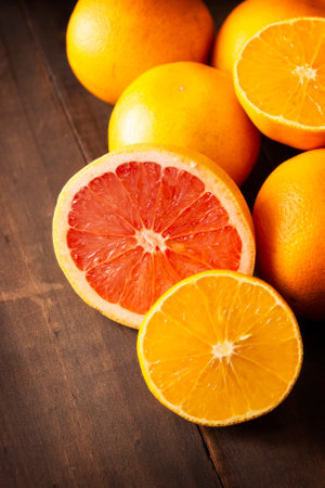 ripe orange and grapefruit slices and several whole oranges on brown rustic wooden table with copy spaceの写真素材