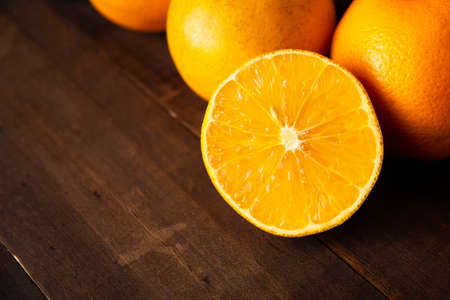 close up of a ripe orange cut in half on brown rustic wooden tableの写真素材