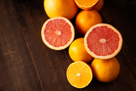 top view image of ripe orange and grapefruit slices and several whole oranges on brown rustic wooden table with copy spaceの写真素材