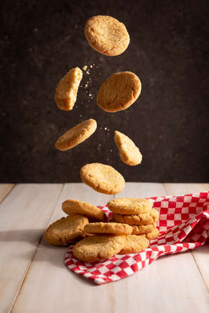 Creative image of homemade butter cookies falling on white wooden rustic tableの写真素材