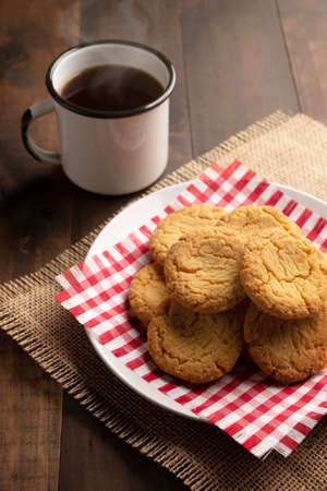Homemade crunchy cookies and a black coffee cup on wooden rustic tableの写真素材