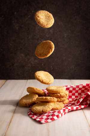 Creative image of homemade butter cookies falling in stack on white wooden rustic tableの写真素材