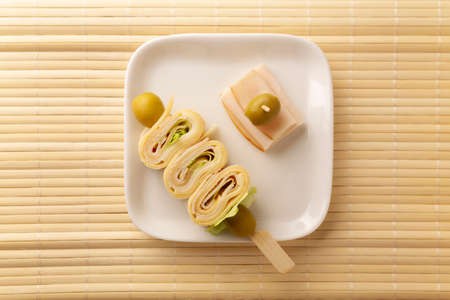 Top view of Party Snacks. Crepe Rolls with ham and cheese on a stick decorated with oliveの写真素材