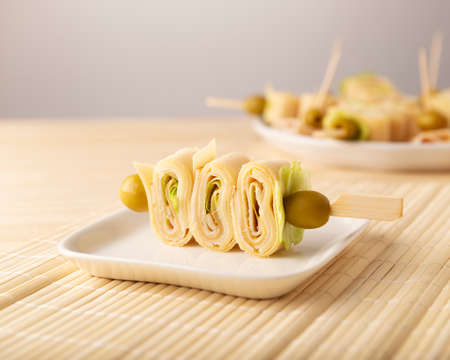 Close Up of Party Snacks. Crepe Rolls with ham and cheese on a stick decorated with oliveの写真素材