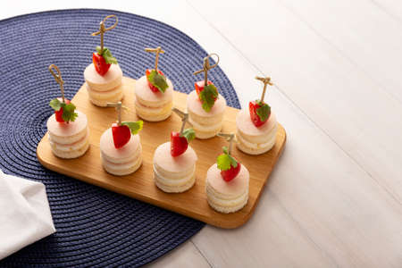 Delicious Party Snacks. Round mini sandwiches with ham and cheese decorated with cherry tomato on a bamboo stickの写真素材