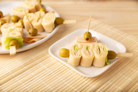 Party Snacks. Crepe Rolls with ham and cheese on a stick decorated with oliveの写真素材