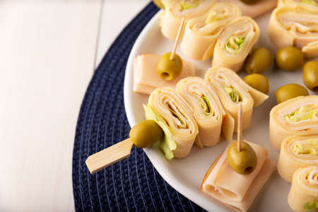 Party Snacks. Crepe Rolls with ham and cheese on a stick decorated with oliveの写真素材