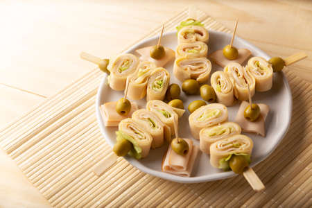 Party Snacks. Crepe Rolls with ham and cheese on a stick decorated with oliveの写真素材