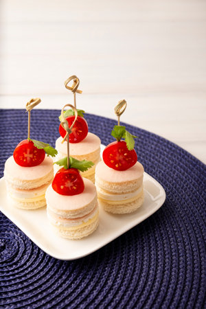 Delicious Party Snacks. Round mini sandwiches with ham and cheese decorated with cherry tomato on a bamboo stickの写真素材