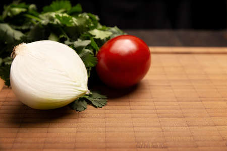 fresh raw middle onion, tomato and cilantro on bamboo wooden board with copy space. Basic ingredients for mexican foodの写真素材