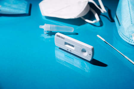 Close up image of Rapid test kit device for showing positive result. Lab card kit test for SARS-CoV-2 virus. Fast test  on blue surfaceの写真素材
