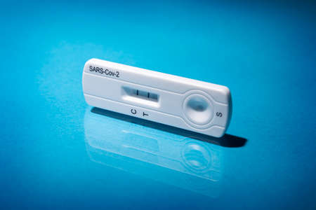 Close up image of Rapid test device for  showing negative result. Lab card kit test for virus SARS-CoV-2 virus.  Fast test  on blue surfaceの写真素材