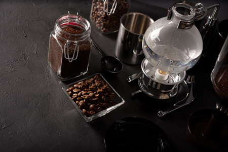 Vacuum coffee maker also known as vac pot, siphon or syphon coffee maker and toasted coffee beans on rustic black stone table. Copy space for your textの写真素材