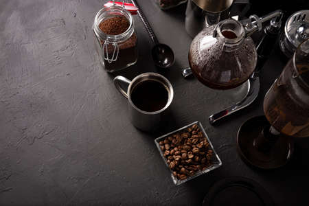 Vacuum coffee maker also known as vac pot, siphon or siphon coffee maker. Metallic cup and toasted coffee beans on rustic black stone table. Copy space for your textの写真素材
