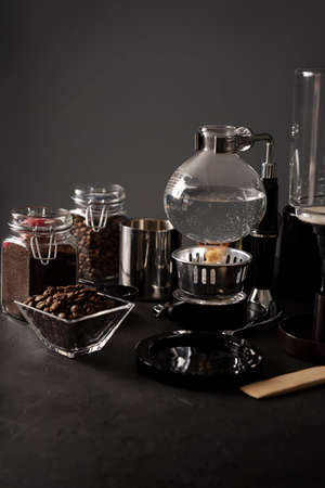 Vacuum coffee maker also known as vac pot, siphon or syphon coffee maker and toasted coffee beans on rustic black stone table. Copy space for your textの写真素材