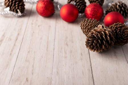 Pine cones and red christmas balls for christmas decoration on rustic white wooden background. Copy space for your textの写真素材