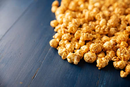 Heap of Caramel Corn Background on blue rustic table. Close up. Copy space for your text.の写真素材